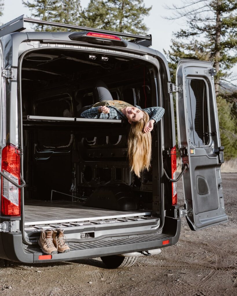 A copywriter hangs out of the back of her converted van.