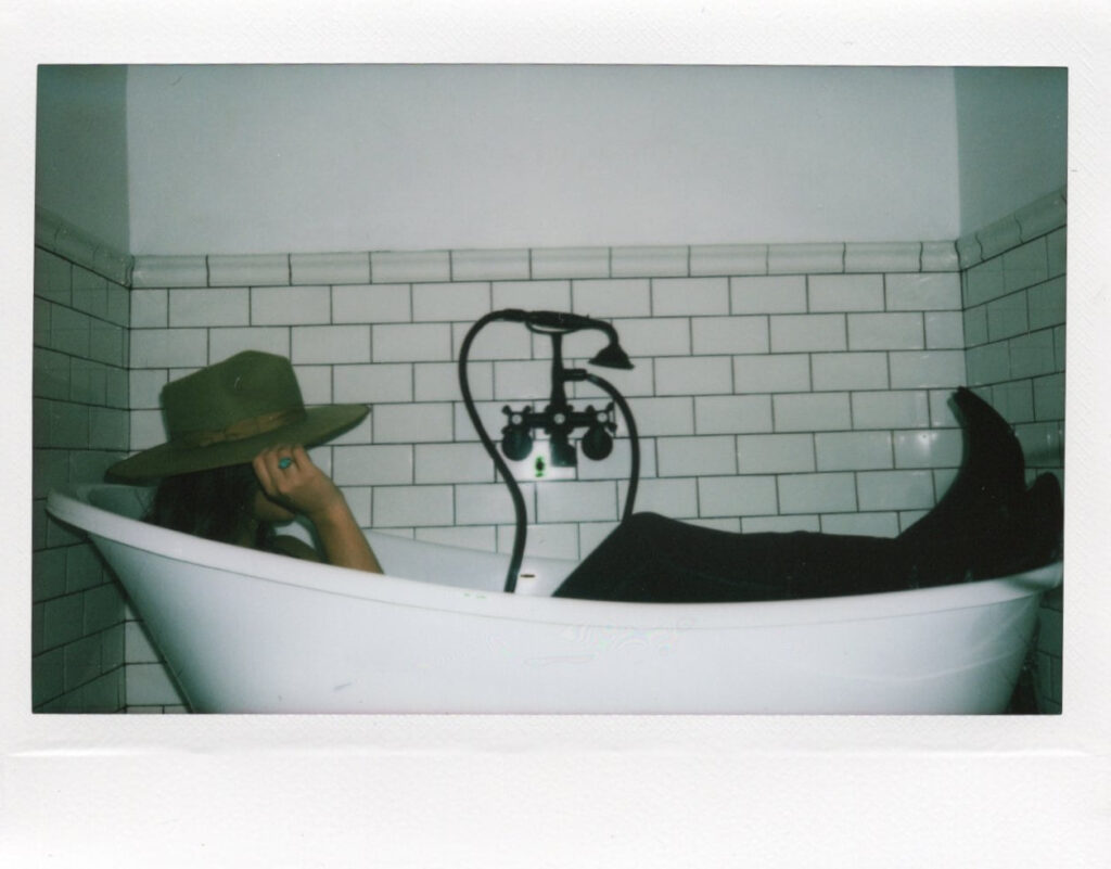 A copywriter poses for a brand photo in a bathtub.