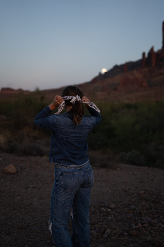 A sales copywriter for small businesses ties up her hair in a white and black bandana while looking at the desert.
