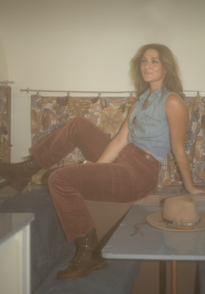 A copywriter sits on the table inside a retro 70s camper during her small business brand shoot.
